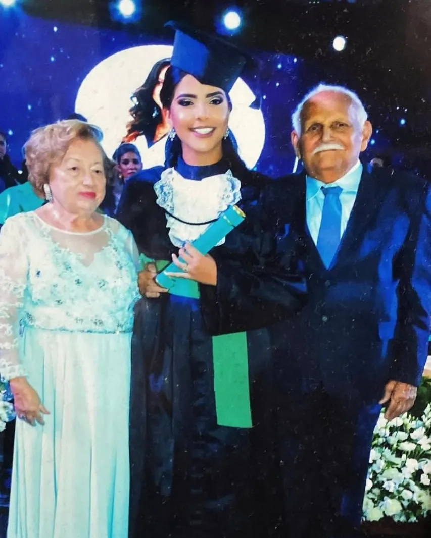 Eu na formatura em Medicina, de beca e com o diploma na mão, entre a minha avó, de vestido claro, e o meu avô, de terno azul